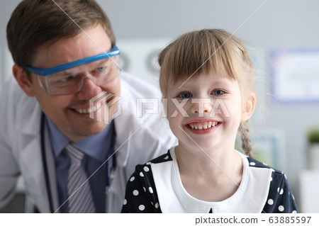 Smiling male doctor looking healthy happy child 63885597