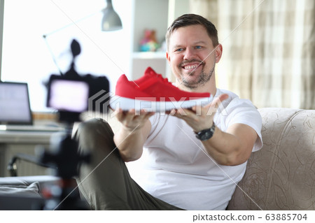 Man in an apartment is filming review new sneakers Man in an apartment is filming review new sneakers 63885704