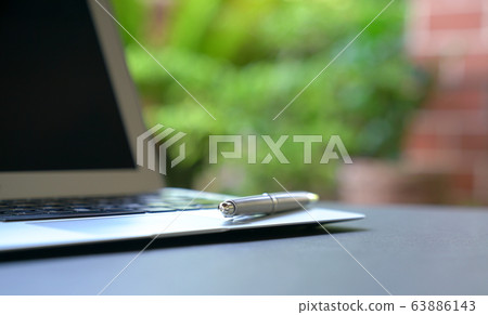 Writing pen on top of computer laptop with green 63886143