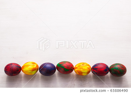 Holidays, traditions and Easter concept - Multi-colored decorative colourful eggs on white background with copy space. Top view. Holidays, traditions and Easter concept - Multi-colored decorative colourful eggs on white background with copy space. Top view. 63886490