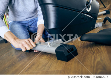man assembling a stationary bicycle man assembling a stationary bicycle 63886803