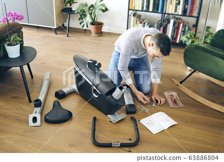 man assembling a stationary bicycle man assembling a stationary bicycle 63886804