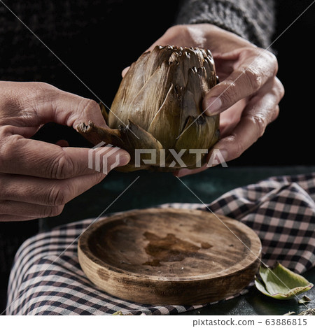 man peeling a roasted artichoke 63886815