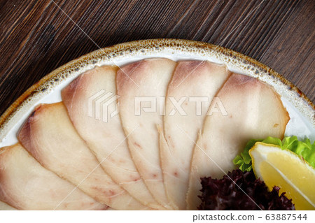 White and red fish sliced in thin slices on a brown wooden background. restaurant menu White and red fish sliced in thin slices on a brown wooden background. restaurant menu 63887544