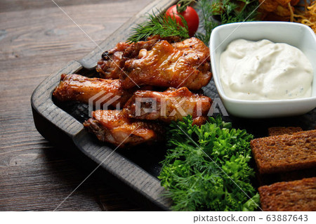Hot appetizer on a wooden black plate on a dark wooden background. Restaurant menu 63887643