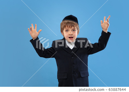 Portrait of a young orthodox jewish boy isolated on blue studio background, meeting the Passover Portrait of a young orthodox jewish boy isolated on blue studio background, meeting the Passover 63887644