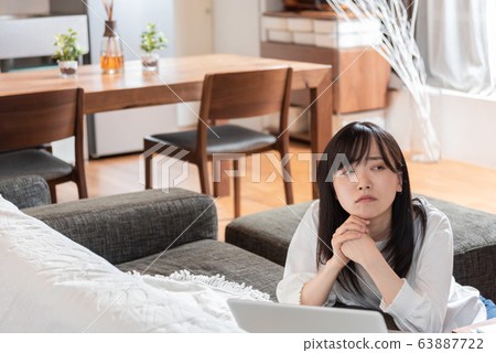 Young woman thinking in living room Young woman thinking in living room 63887722