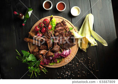 Meat on the bone on a wooden board . catering menu 63887809