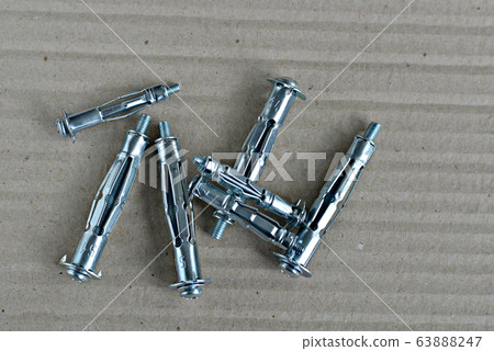 Metal expansion bolt shields or anchor bolts on a gray table. Metal expansion bolt shields or anchor bolts on a gray table. 63888247