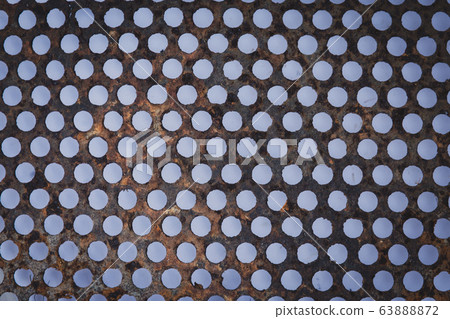Background sheet of metal covered with lines of circular holes. 63888872