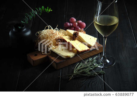 Glass of cold white wine with cheese snack on a wooden. catering menu Glass of cold white wine with cheese snack on a wooden. catering menu 63889077