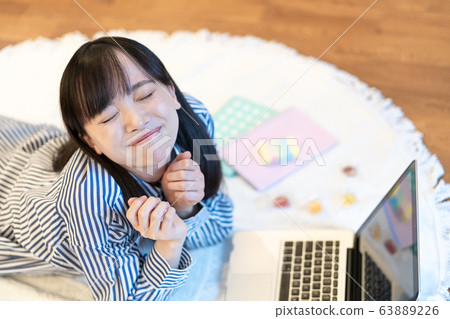 Young woman eating sweets while lying in the living room Young woman eating sweets while lying in the living room 63889226