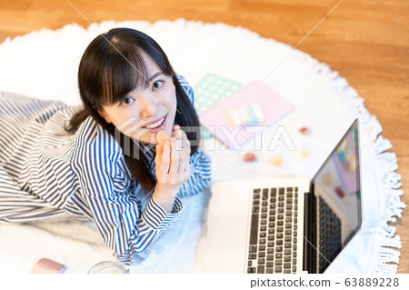 Young woman eating sweets while lying in the living room Young woman eating sweets while lying in the living room 63889228