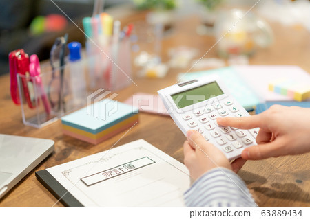 Calculator at hand of young woman keeping household account book 63889434