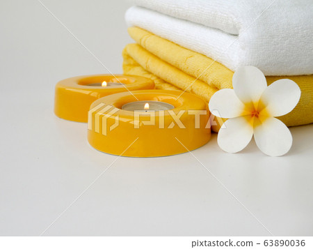 Towels, two candles and frangipani flower 63890036