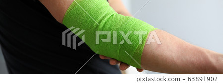 Man shows stretching on arm with elastic bandage 63891902