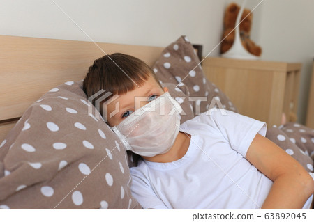 A boy in a respiratory mask sits in quarantine at home 63892045