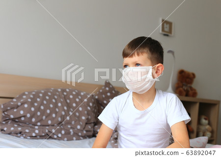 A boy in a respiratory mask sits in quarantine at home 63892047