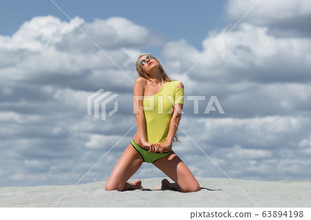 Seductive woman in stylish swimsuit kneeling in 63894198