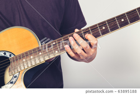 man playing guitar acoustic wearing t-shirt close up shot on white background man playing guitar acoustic wearing t-shirt close up shot on white background 63895188