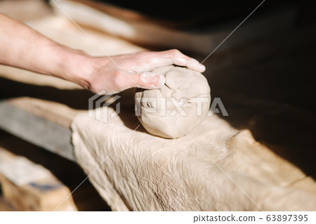 Close up of man works with clay. Male potter kneads and moistens the clay before work, toned 63897395