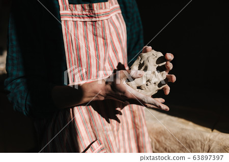 Close up of man works with clay. Male potter kneads and moistens the clay before work, toned Close up of man works with clay. Male potter kneads and moistens the clay before work, toned 63897397