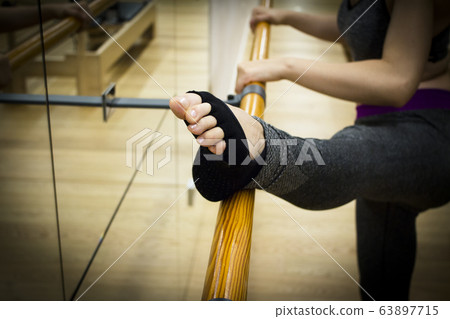 Female dancer doing stretching on the ballet barre 63897715