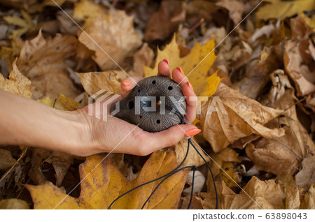 Female hand with orange manicure holds ceramic ocarina in the forest during autumn. Relaxing tranquil scene, traditional music concepts Female hand with orange manicure holds ceramic ocarina in the forest during autumn. Relaxing tranquil scene, traditional music concepts 63898043