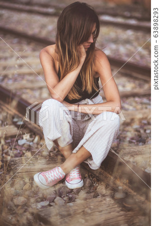 Sad young woman sitting on the railway. 63898293