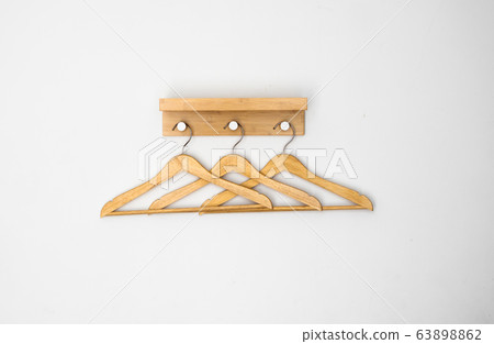 Clothes wooden hangers on a white wall. Clothes wooden hangers on a white wall. 63898862