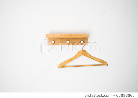 Clothes wooden hanger on a white wall. Clothes wooden hanger on a white wall. 63898863