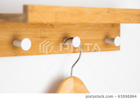 Clothes wooden hanger on a white wall. Clothes wooden hanger on a white wall. 63898864