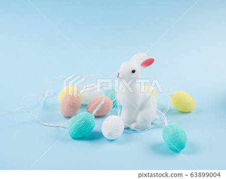 Easter bunny with colorful eggs on blue backdrop 63899004