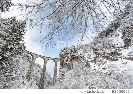 The Landwasser Viaduct with Railway without famous train at winter, landmark of Switzerland, snowing, river and mountains 63900031