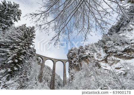 The Landwasser Viaduct with Railway without famous train at winter, landmark of Switzerland, snowing, river and mountains 63900178
