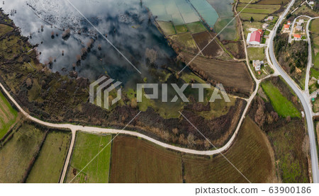 Flight over the flooded valley in Greece. The flooded fields, roads, mountains on background, the inhabited settlement. Reflection of mountains in water 63900186