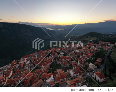 Aerial view of Delphi, Greece, the Gulf of Corinth, orange color of clouds, mountainside with layered hills beyond with rooftops in foreground 63900187