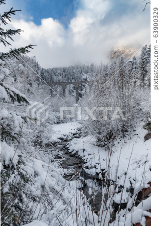 The Landwasser Viaduct with Railway without famous train at winter, landmark of Switzerland, snowing, river and mountains 63900329