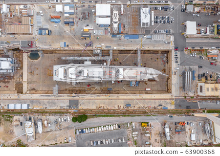 Aerial view of sea dry dock in La Ciotat city, France, the cargo crane, boats on repair, a luxury sail yacht and motor yacht, mountain is on background, shipyard Aerial view of sea dry dock in La Ciotat city, France, the cargo crane, boats on repair, a luxury sail yacht and motor yacht, mountain is on background, shipyard 63900368