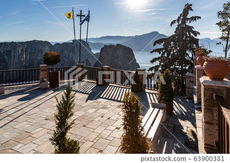 Kalambaka, Greece, Terrace of monastery Varlaam and breathtaking pictures of valley and landmark canyon of Meteora at sunset, magic shadows, flags, Benches 63900381