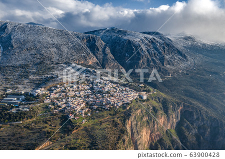 Aerial view of Delphi, Greece at sunrise, the Gulf of Corinth, Morning fog over mountains, hoarfrost on roofs, mountainside with layered hills beyond with rooftops in foreground 63900428