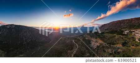 Aerial view of Delphi, Greece, the Gulf of Corinth, orange color of clouds, mountainside with layered hills beyond with rooftops in foreground 63900521