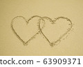 Two hearts drawn on the sand beach representing 63909371