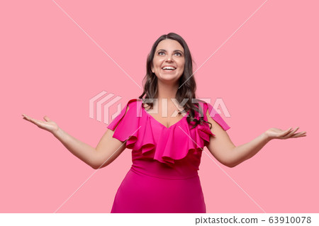 Woman in pink standing ecstatic with arms spread to the sides. 63910078