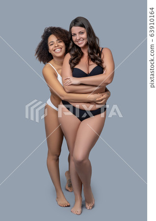 Young girls standing close embraced in underwear. 63910164