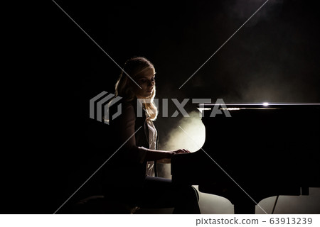 Female keyboards player on stage during concert, backlight Female keyboards player on stage during concert, backlight 63913239