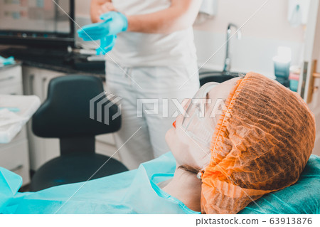 A cute girl is sitting in a dentist chair and 63913876