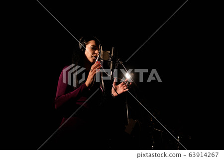 Portrait of woman recording a song in a professional studio 63914267