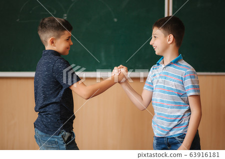 Two school boys stand in front of balckboard in class room 63916181