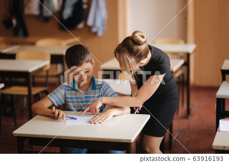 Teacher helping school kids writing test in classroom. education, elementary school, learning and people concept 63916193